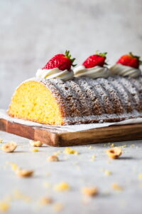 Polenta cake with a slice cut off and topped with strawberries.